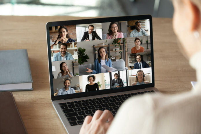 Close up rear view of woman have webcam virtual digital conference with multiracial diverse colleagues on laptop. Female employee speak talk on video call or online team meeting with coworkers.