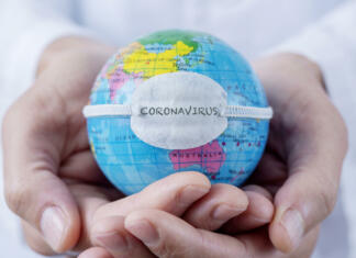 Špancem je maska nova normalnost closeup of a caucasian doctor man holding a world globe with a protective mask with the word coronavirus written in it