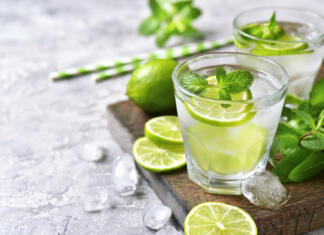 Najboljši mojito recepti Cold refreshing summer lemonade mojito in a glass on a grey concrete or stone background.