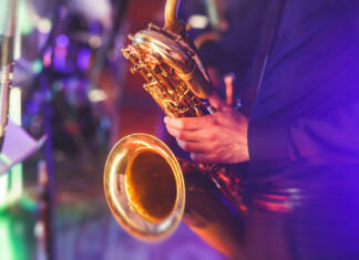 Dan in noč. Belo in črno. Concert view of a saxophone player with vocalist and musical jazz band in the background"n