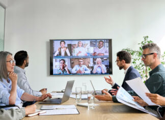Te mika tujina? Spoznaj jo na Mesecu mednarodnih izzivov ŠOU v Ljubljani! Diverse company employees having online business conference video call on tv screen monitor in board meeting room. Videoconference presentation, global virtual group corporate training concept.