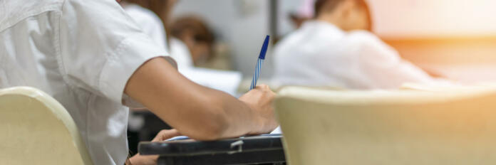 Exam with school students in class back view of the classroom of young people having stress doing examination admission test for university and college education background