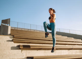 Zakaj začeti trenirati? Fit Young woman in sportswear doing yoga, fitness exercise on the street. Warming up your muscles before an intense workout in the morning. Sport, Active life, sports training, healthy lifestyle.