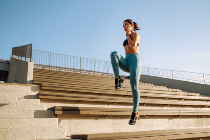 Fit Young woman in sportswear doing yoga, fitness exercise on the street. Warming up your muscles before an intense workout in the morning. Sport, Active life, sports training, healthy lifestyle.