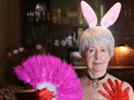 Fun senior woman with bunny ears and feathers hand fan.
