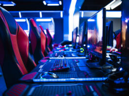 Game room interior with modern ambient lights and powerful super computers, consoles, keyboards for playing video games. Entertaining industry.