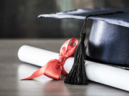 Graduation hat and diploma on table