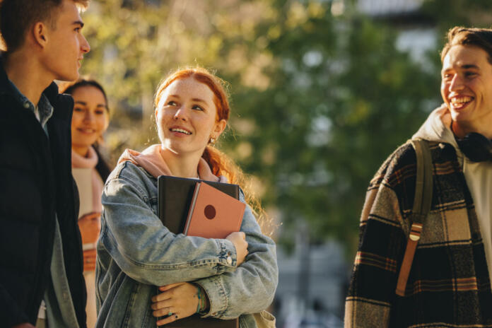 Group of students walking and talking in university campus. Young people walking outdoors in high school campus.