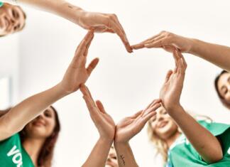 POROČILO IN KLIC NA POMOČ Group of young volunteers woman smiling happy make heart symbol with hands together at charity center.