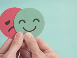 Hands holding sad face hiding behind happy face, bipolar and depression, mental health, split personality,  mood change,
