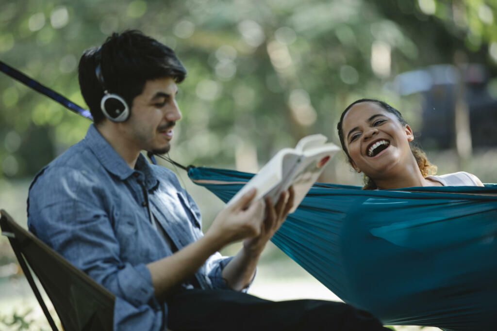 Happy multiethnic couple with book and hammock