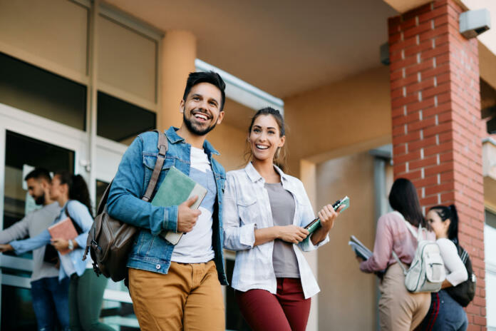 Happy university student and his female friend walking after the lecture at campus.