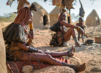 Odprava Namibija Himba women sitting outside their huts in a traditional Himba village near Kamanjab in northern Namibia, Africa.