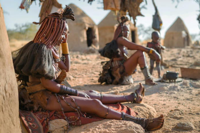 Himba women sitting outside their huts in a traditional Himba village near Kamanjab in northern Namibia, Africa.
