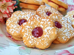 Linzer cookies sprinkled with powdered sugar on a plate