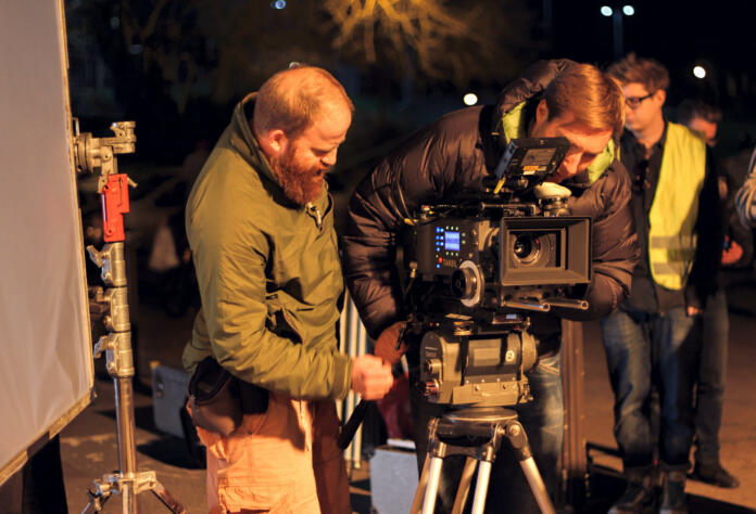 London, UK - March 30, 2012:  Film Crew On Location Night Shoot. DoP and assistant preparing to shoot using 4k camera.