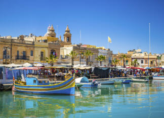 Najlepše plaže na Malti Malta - Marsaxlokk market with traditional Luzzu fishing boats on a beautiful summer day withblue sky and green sea