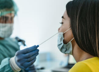 Ponovno dovoljeno prehajanje občin, odprti tudi frizerski saloni Medical worker wearing personal protective equipment doing corona virus swab on female patient - Covid19 test and health care concept