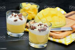 Mousse of mango in a glass jars on a wooden table