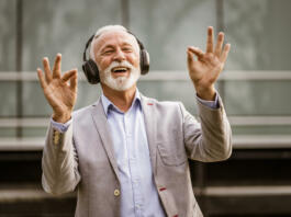 Outdoor portrait of senior businessman who is enjoying music on headphones.
