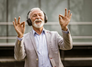Preko glasu bi lahko ugotovili bolezni? Outdoor portrait of senior businessman who is enjoying music on headphones.