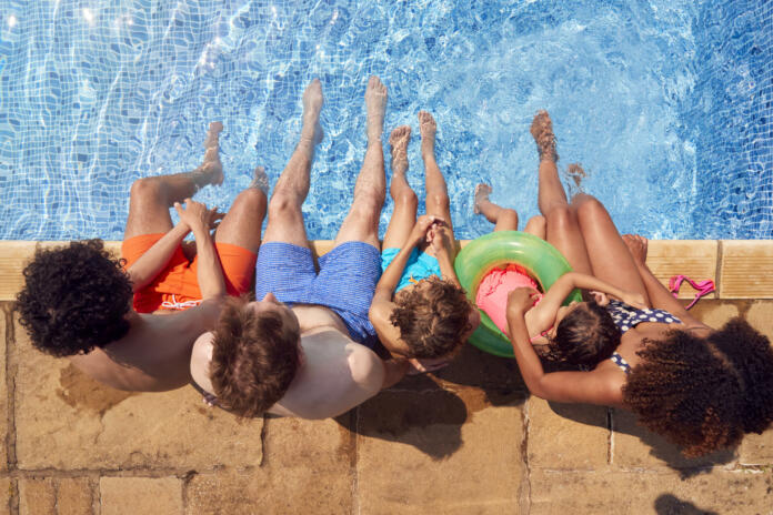 Overhead View Of Family With Children Having Fun In Swimming Pool On Summer Vacation