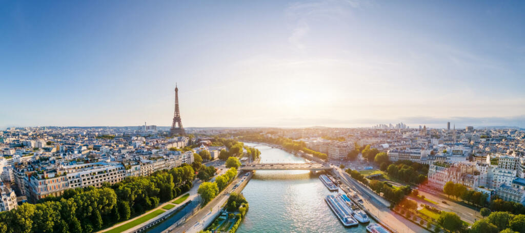 Paris aerial panorama with river Seine and Eiffel tower, France. Romantic summer holidays vacation destination. Panoramic view above historical Parisian buildings and landmarks with blue sky and sun