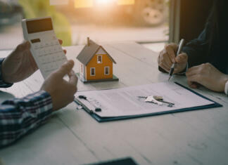 Kako najeti stanovanje? Real estate professionals offer their clients contracts to discuss home purchases, insurance or real estate loans. Home sales agents sit at the office with new home buyers in the office.