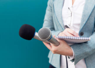 Revija Študent išče novinarje Reporter or TV journalist at news conference, holding microphone and writing notes