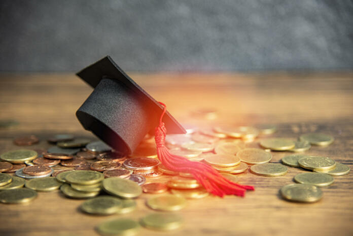 Scholarship for education concept with graduation cap on money coin wooden table