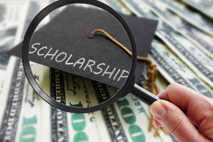 Scholarship graduation cap on money with magnifying glass