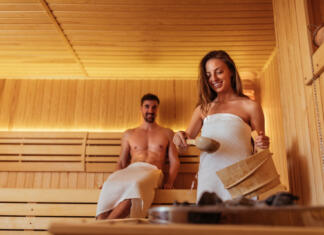 Katero savno izbrati? Shot of a young woman pouring water over sauna rocks
