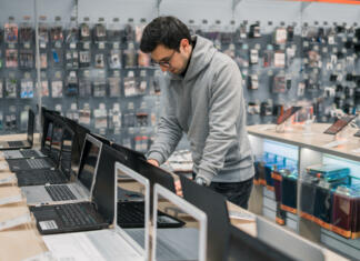 Na kaj moram biti pozoren pri nakupu namiznega računalnika? Smart modern male customer choosing laptop in the computer shop. difficult decision. He is opening notebook for checking.