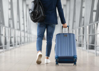 Kam za prvi maj? Unrecognizable Man With Bag And Suitcase Walking In Airport Terminal, Rear View Of Young Male On His Way To Flight Boarding Gate, Ready For Business Travel Or Vacation Journey, Cropped, Copy Space