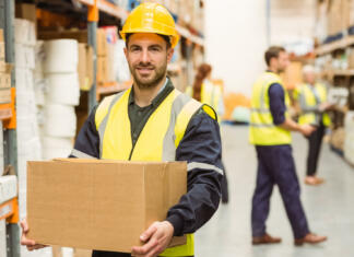 Ali izbira študija vpliva na nadaljnjo kariero? Warehouse worker smiling at camera carrying a box in a large warehouse