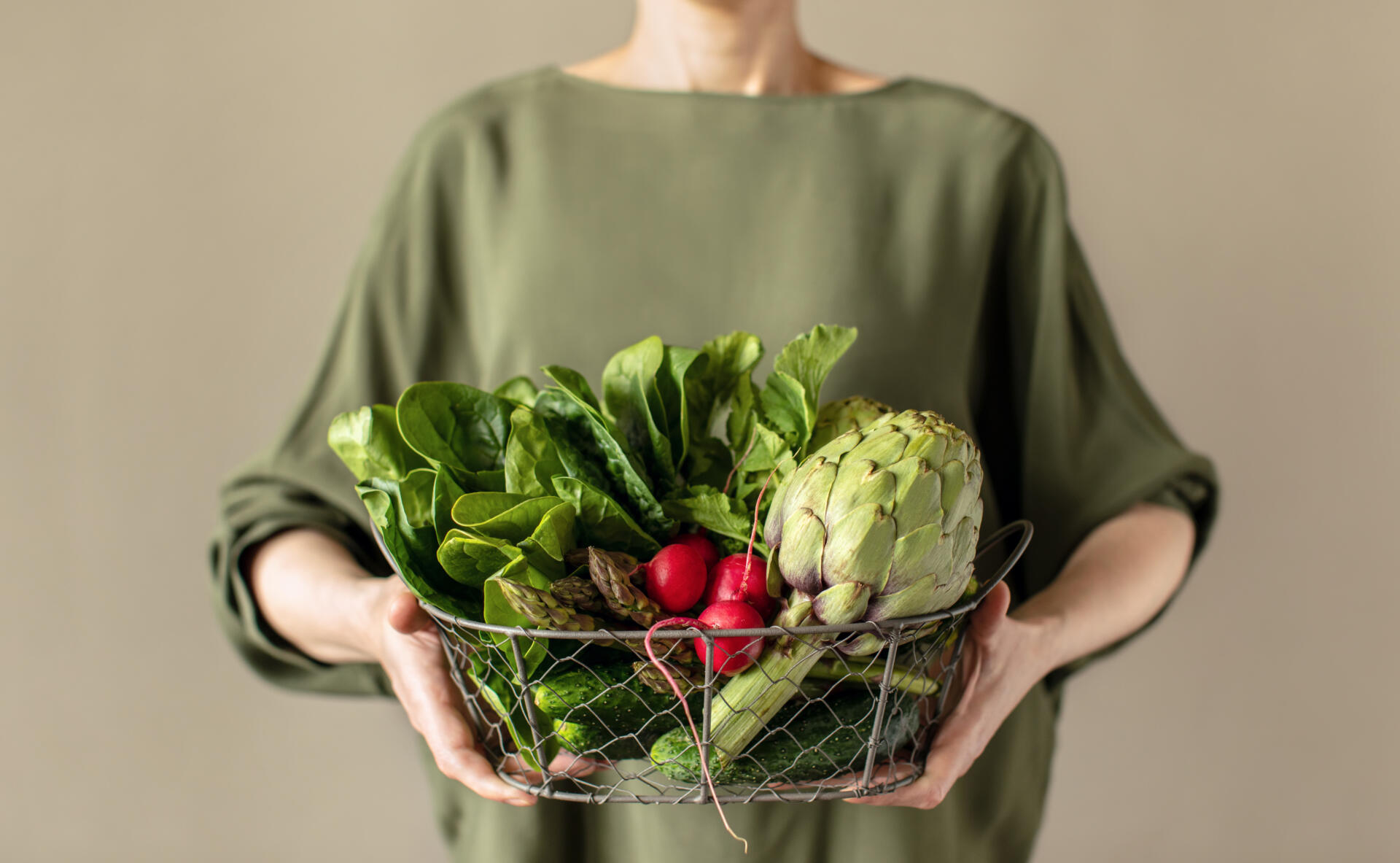 Woman holding a basket full of fresh veggie produce, healthy food, or healthy sustainable living concept