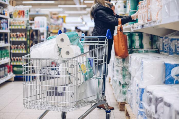 Woman shopping at supermarket choosing toilet paper. The most important thing is to make a stock of toilet paper during pandemic.