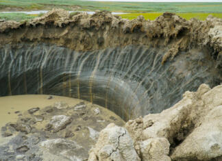 Sibirska »vrata v pekel« se povečujejo YAMAL PENINSULA, RUSSIA - JUNE 18, 2015: Helicopter expedition to the giant funnel of unknown origin. Crater view.