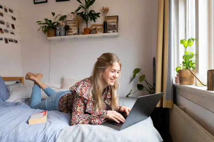 young-university-student-following-lecture-on-her-laptop-on-the-bed-stockpack-istock Young university student following lecture on her laptop on the bed