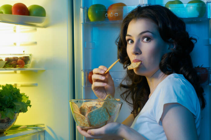 a hungry girl opens the fridge