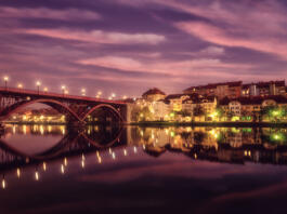 Amazing view of Maribor Old city, Main bridge (Stari most) on the banks of Drava river before sunrise, Slovenia. Scenic cityscape with dramatic cloudy sky and reflection, outdoor travel background