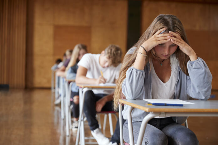 Anxious Teenage Student Sitting Examination In School Hall