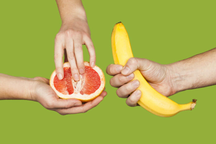 Banana and grapefruit in hands isolated on a green background as a symbol of male and female masturbation. Games with the clitoris and touching the penis. Stimulation and orgasm.