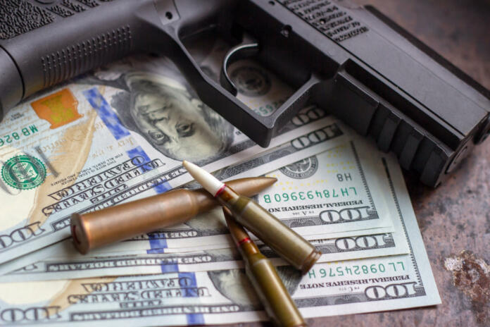 Black gun and weapon bullets on American dollars background. Military industry, war, global arms trade and crime concept
