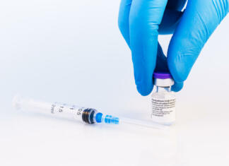 Kako delujejo nova mRNA cepiva in ali so varna? Brasov, Romania - February 21, 2021: Doctor or scientist holding Pfizer-BioNTech Covid-19 vaccine on a white background.