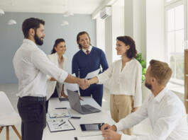 Business partners making deal, shaking hands in negotiation meeting. Smiling male CEO welcoming new female employee to company. Young boss congratulating happy woman with good results and promotion