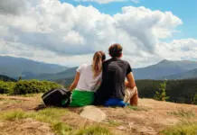 Ali zakon privlačnosti res deluje? Couple of hikers admire view of Carpathian mountains. Happy tourists hug relaxing on top of Hoverla. Traveling in summer Ukraine