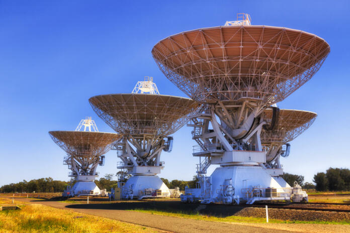 Deep space exploration radio telescopes array on rails in Australian Narrabri CSIRO station against clear blue sky.