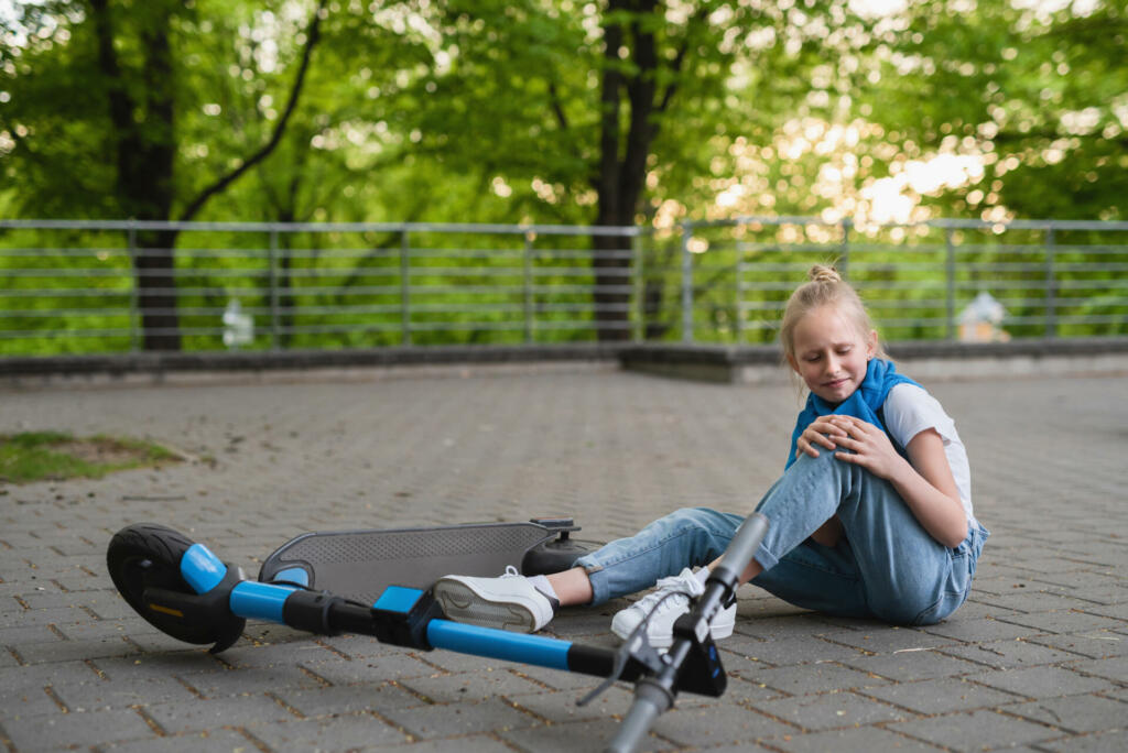 Electric scooter accident - girl suffering of pain after knee injury in city park