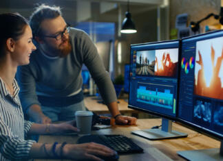 Koliko monitorjev rabim? Female Video and Sound Editor Works With Her Male Colleague on a Project on Her Personal Computer with Two Displays. They Work in a Creative Loft Office.